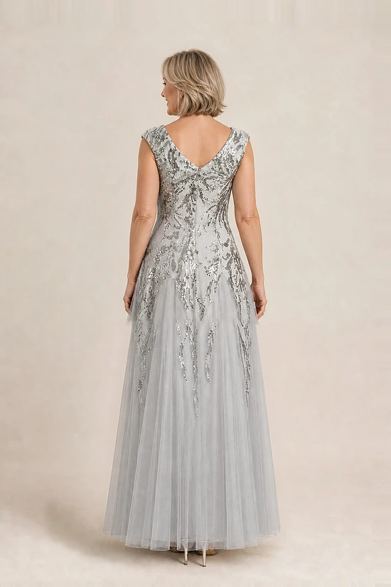 Back view of the silver glitter embroidered gown showing the V-shaped back and the soft trumpet tulle skirt, worn by a mother of the bride
