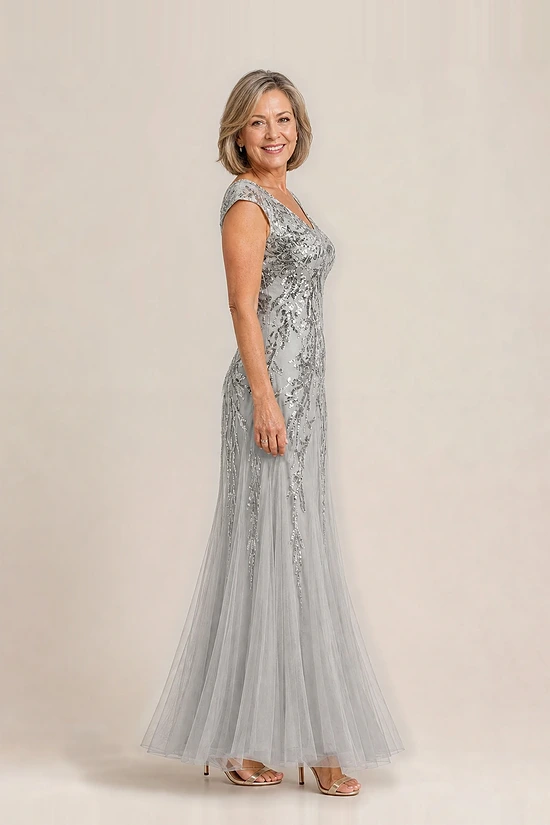 Side view of the silver glitter embroidered gown showing the cap sleeve and the soft trumpet tulle skirt, worn by a mother of the bride