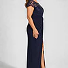 Side view of the navy knotted crepe column gown showing the embroidered cap sleeve, the waist knot and the front slit, worn by a plus-size mother of the bride