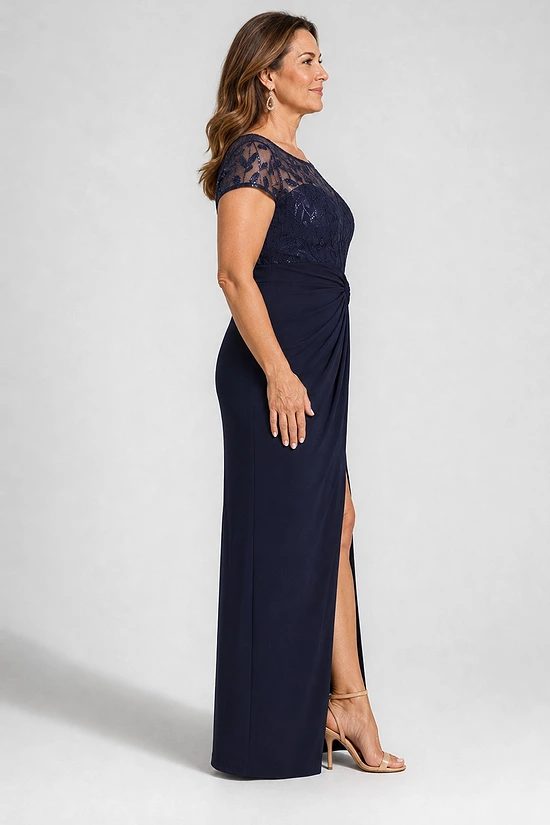 Side view of the navy knotted crepe column gown showing the embroidered cap sleeve, the waist knot and the front slit, worn by a plus-size mother of the bride