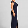 Side view of the navy knotted crepe column gown showing the embroidered cap sleeve, the waist knot and the front slit, worn by a mother of the bride