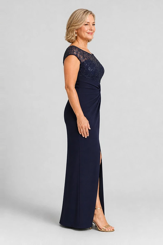 Side view of the navy knotted crepe column gown showing the embroidered cap sleeve, the waist knot and the front slit, worn by a mother of the bride