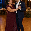 Mother of the groom wearing the burgundy Delphine glitter knit gown by Dressology, dancing with her son at the wedding reception