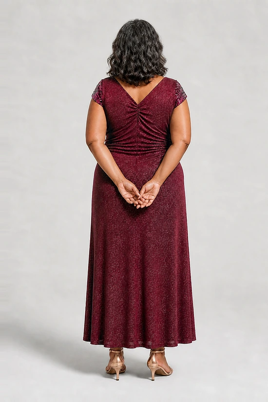 Back view of the Delphine burgundy twist-waist glitter knit gown by Dressology on a plus size model showing the V back and A-line skirt