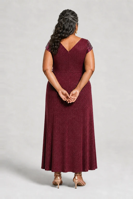 Back view of the Delphine burgundy twist-waist glitter knit gown by Dressology on a plus size model showing the V back and A-line skirt