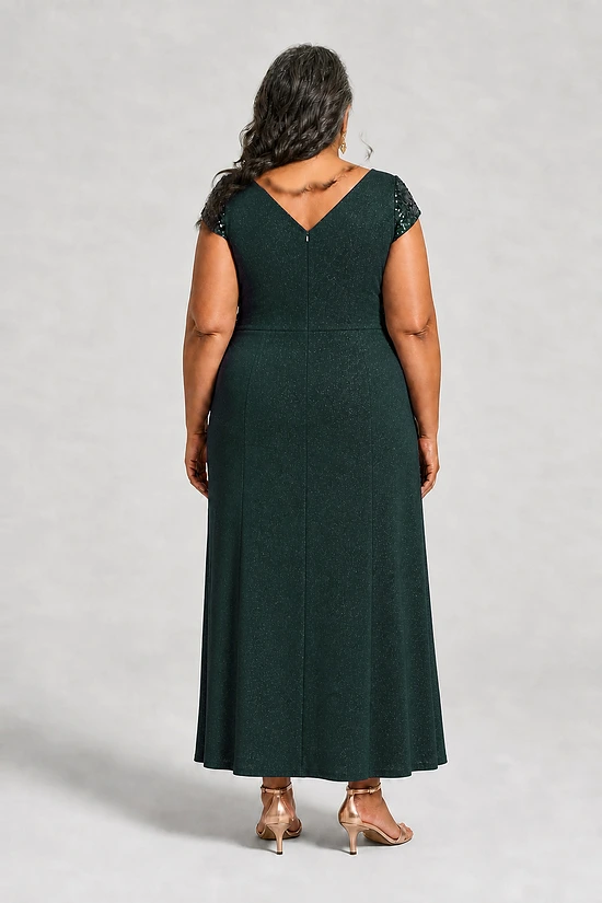 Back view of the Delphine emerald green twist-waist glitter knit gown by Dressology showing the deep V back and plain A-line skirt