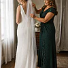 Mother of the bride wearing the emerald green Delphine glitter knit gown by Dressology, settling her daughter's veil in the bridal suite before the wedding