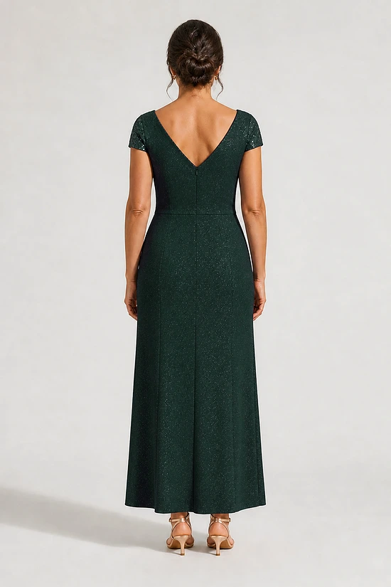 Back view of the Delphine emerald green twist-waist glitter knit gown by Dressology on a regular size model showing the V back and A-line skirt
