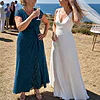 Mother of the bride wearing the teal Delphine glitter knit gown by Dressology, raising a toast with her daughter at the wedding drinks by the sea
