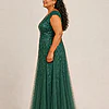 Side view of the emerald green glitter embroidered gown showing the cap sleeve and the soft trumpet tulle skirt, worn by a plus-size mother of the bride
