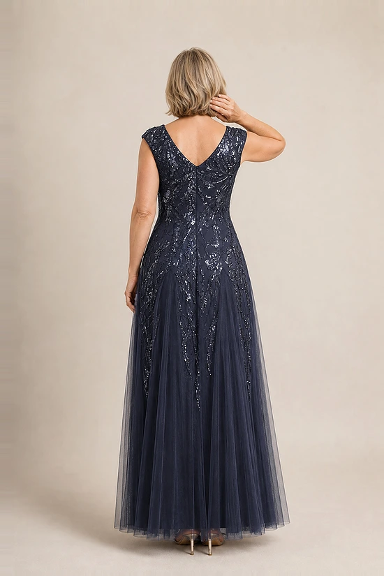 Back view of the navy glitter embroidered gown showing the V-shaped back and the soft trumpet tulle skirt, worn by a mother of the bride