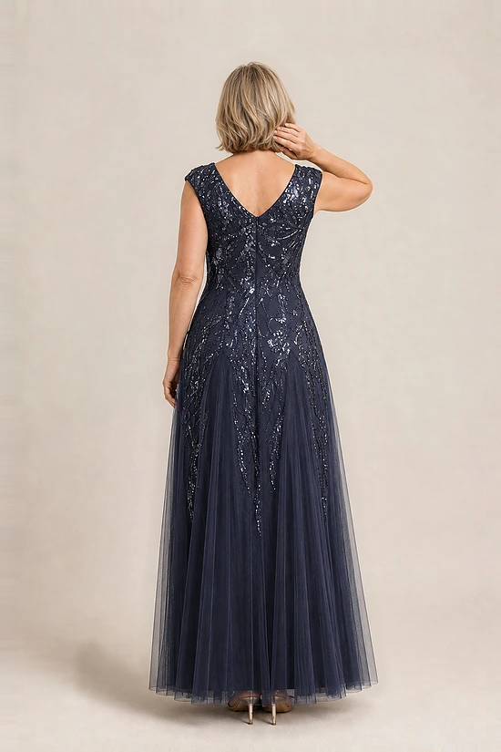 Back view of the navy glitter embroidered gown showing the V-shaped back and the soft trumpet tulle skirt, worn by a mother of the bride