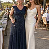 Mother of the bride wearing the navy Sylvie glitter embroidered gown by Dressology, laughing with her daughter at a vineyard reception